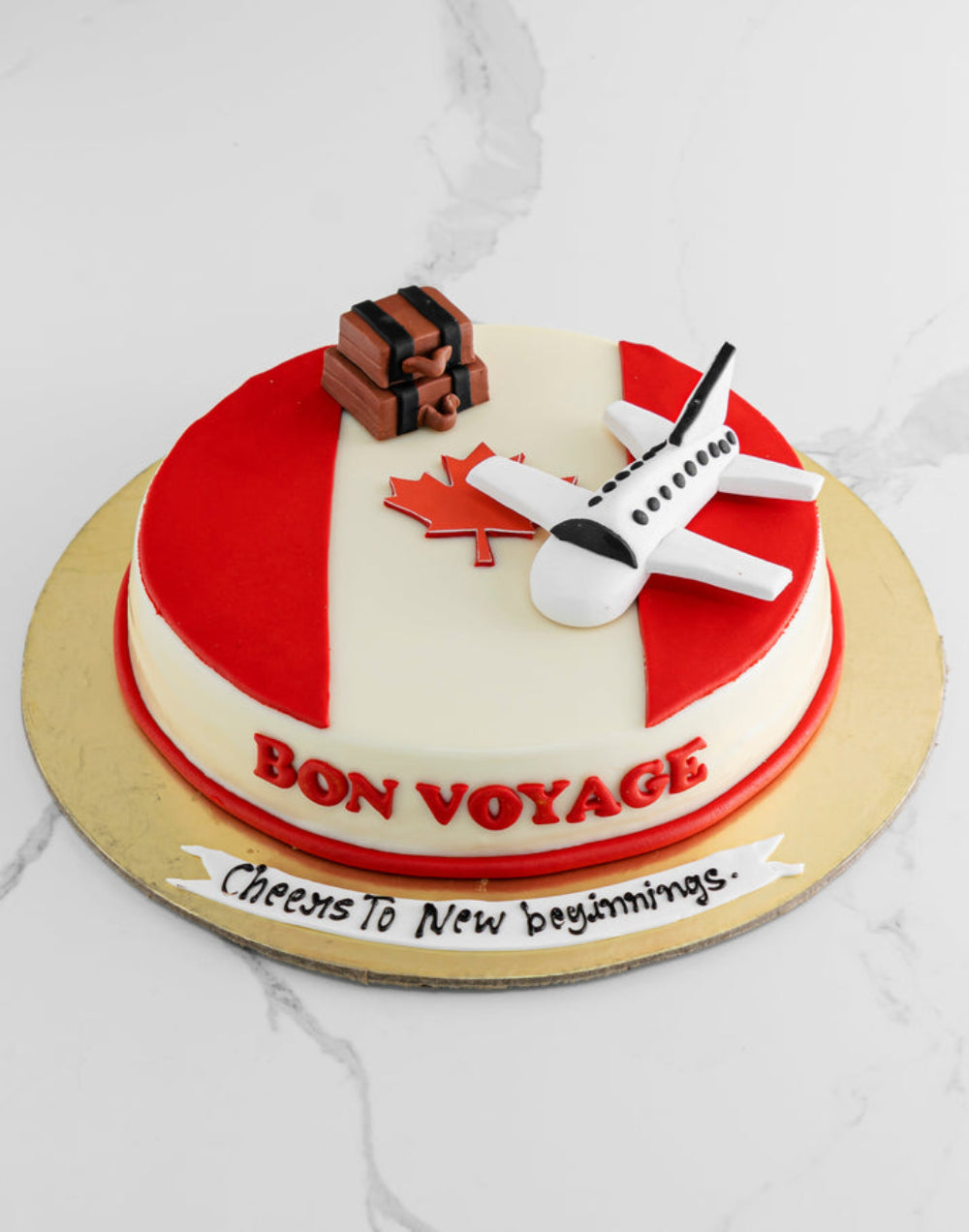 Travel theme designer cake with airplane topper, suitcase decoration, and “Bon Voyage” message, perfect for farewell or journey celebration.