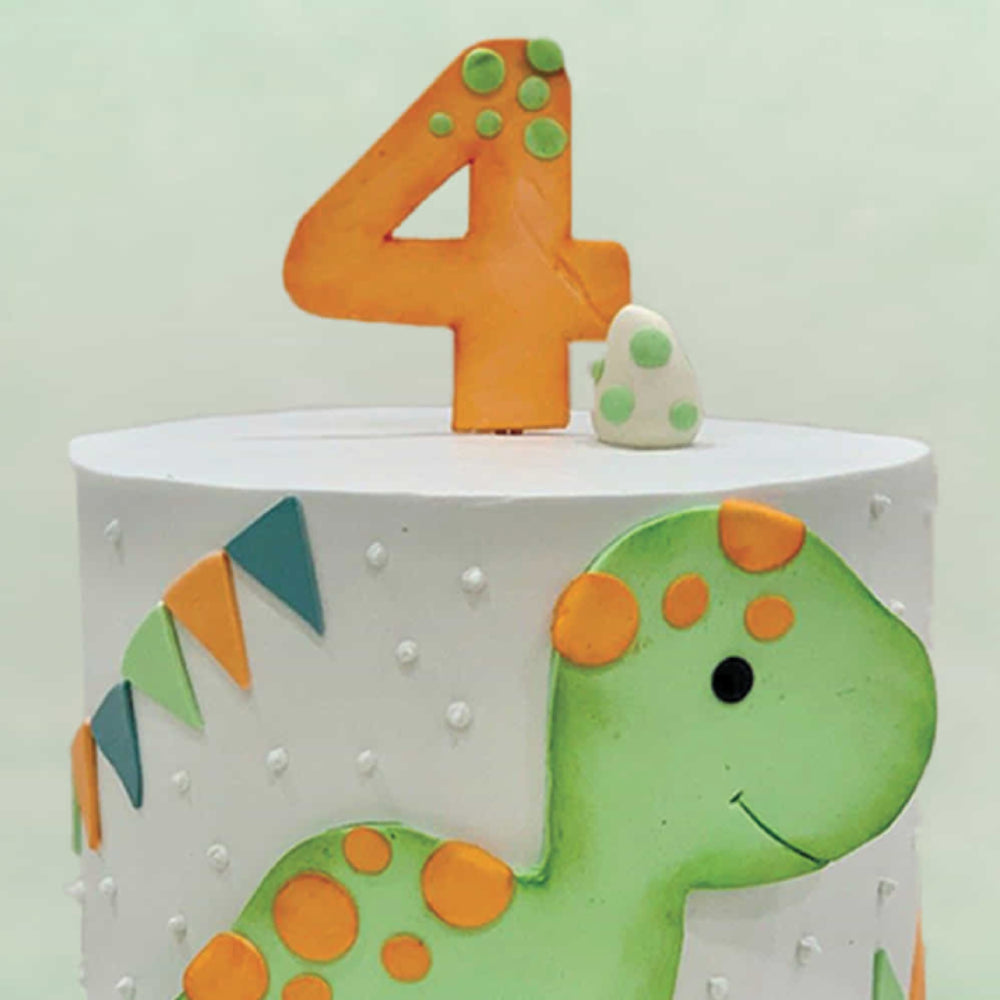 Children's birthday cake with dinosaur design and number 4 candle on a light green background