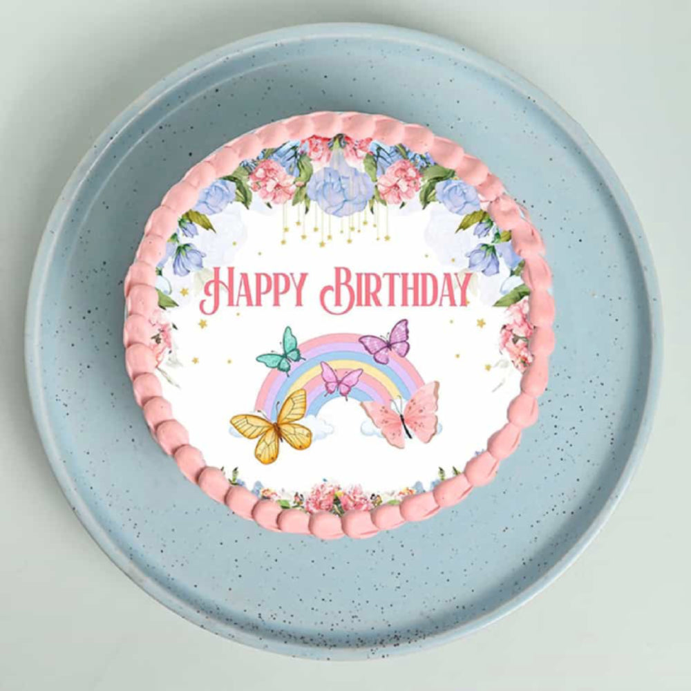 Decorative cake with 'Happy Birthday' text, flowers, and a rainbow on a blue plate.