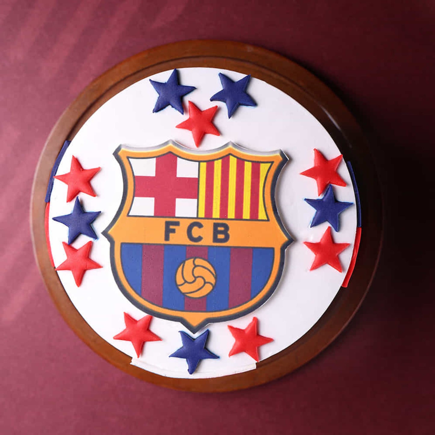 FC Barcelona logo with stars on a circular wooden plaque against a red background