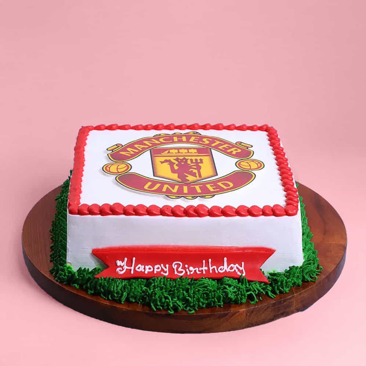 Square birthday cake with Manchester United logo on a pink background