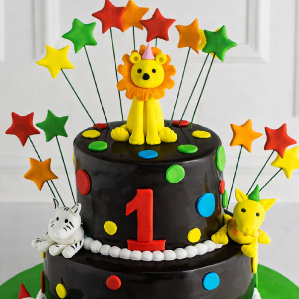 Colorful two-tier kids birthday designer cake with a lion topper, star decorations, number one theme, and animal figures, perfect for a first birthday celebration.