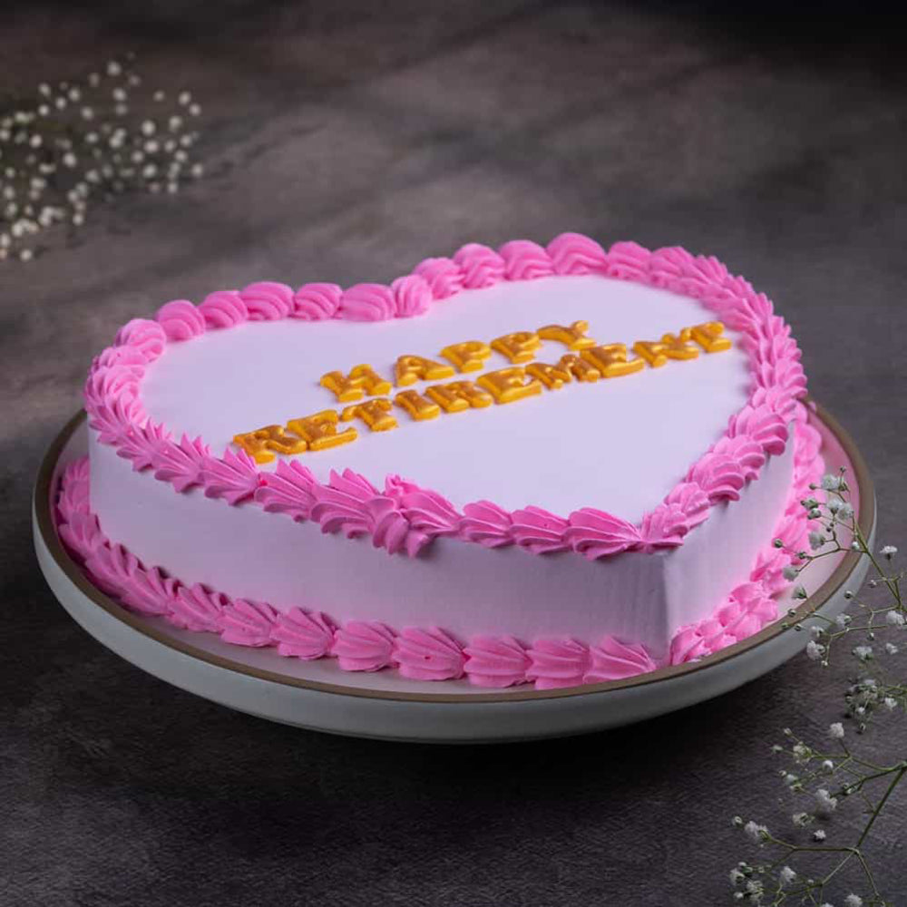 Pink heart-shaped cake with gold "Happy Retirement" written. side angle view