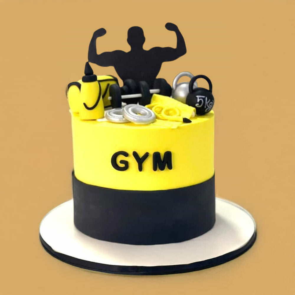 Yellow and black round cake with a gym theme, featuring weights, a kettlebell, a water bottle, and a flexing silhouette topper, with the word “GYM” on the front.