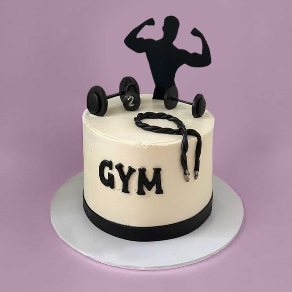 White round cake with a gym theme, featuring dumbbells, a rope, and a silhouette of a flexing figure on top, with the word “GYM” on the side.
