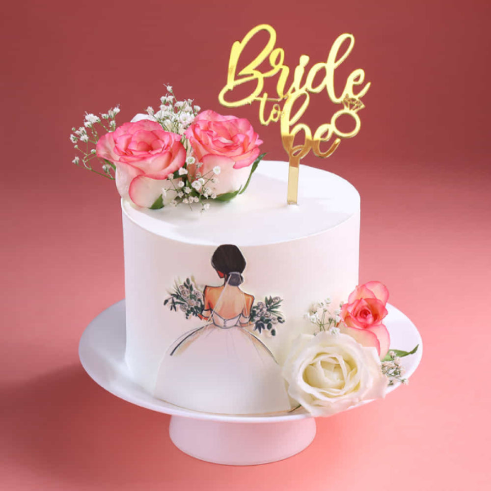 Elegant bride to be designer cake with floral decoration and gold topper, perfect for bridal shower celebrations in Delhi.