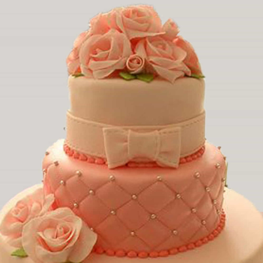 Two-tier pink and white designer cake with rose decorations and bow design, perfect for weddings and special occasions in Delhi.