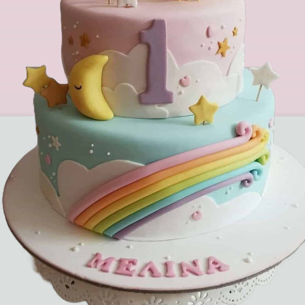 Colorful birthday cake with rainbow, moon, and stars on a pink background
