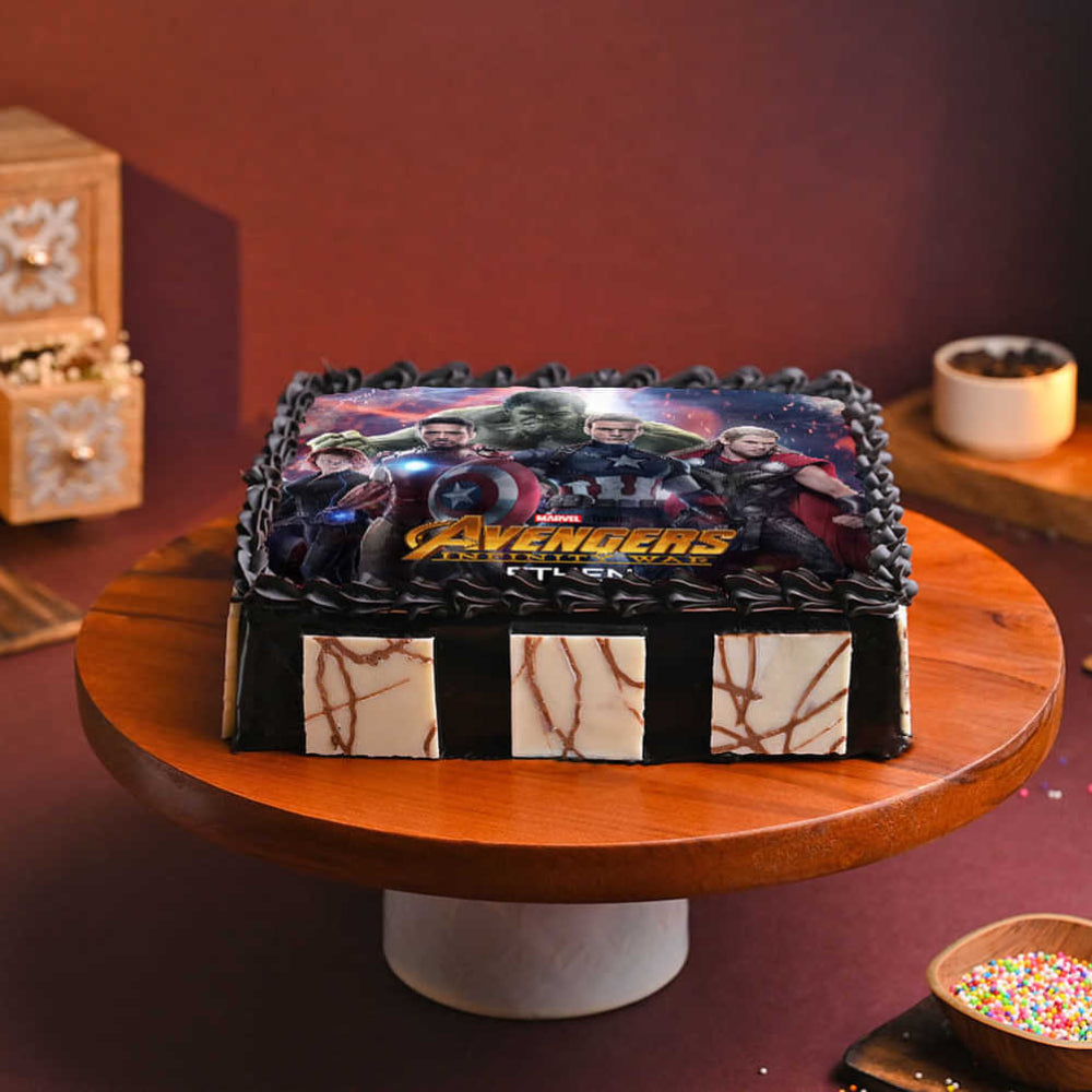 Avengers-themed birthday cake on a wooden cake stand with a red background