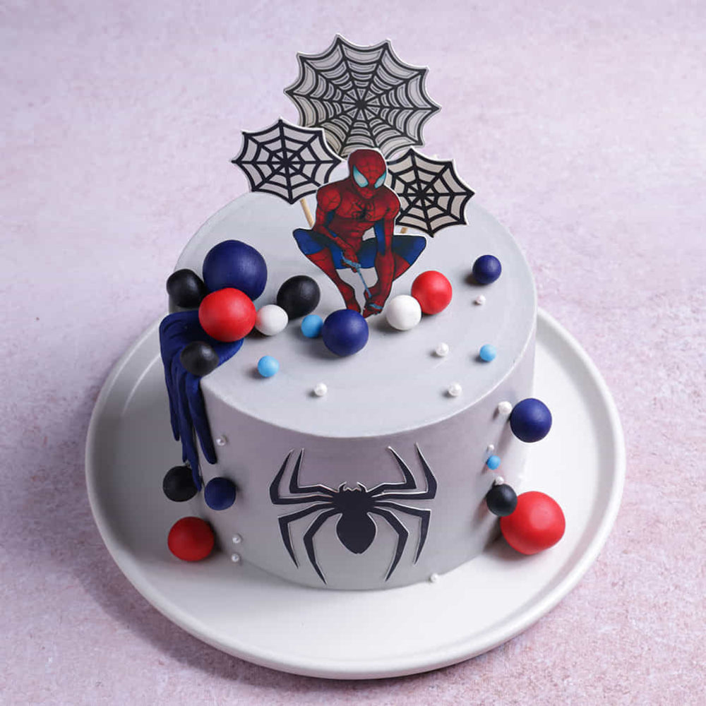 Spider-Man themed cake with colorful decorations on a light purple background