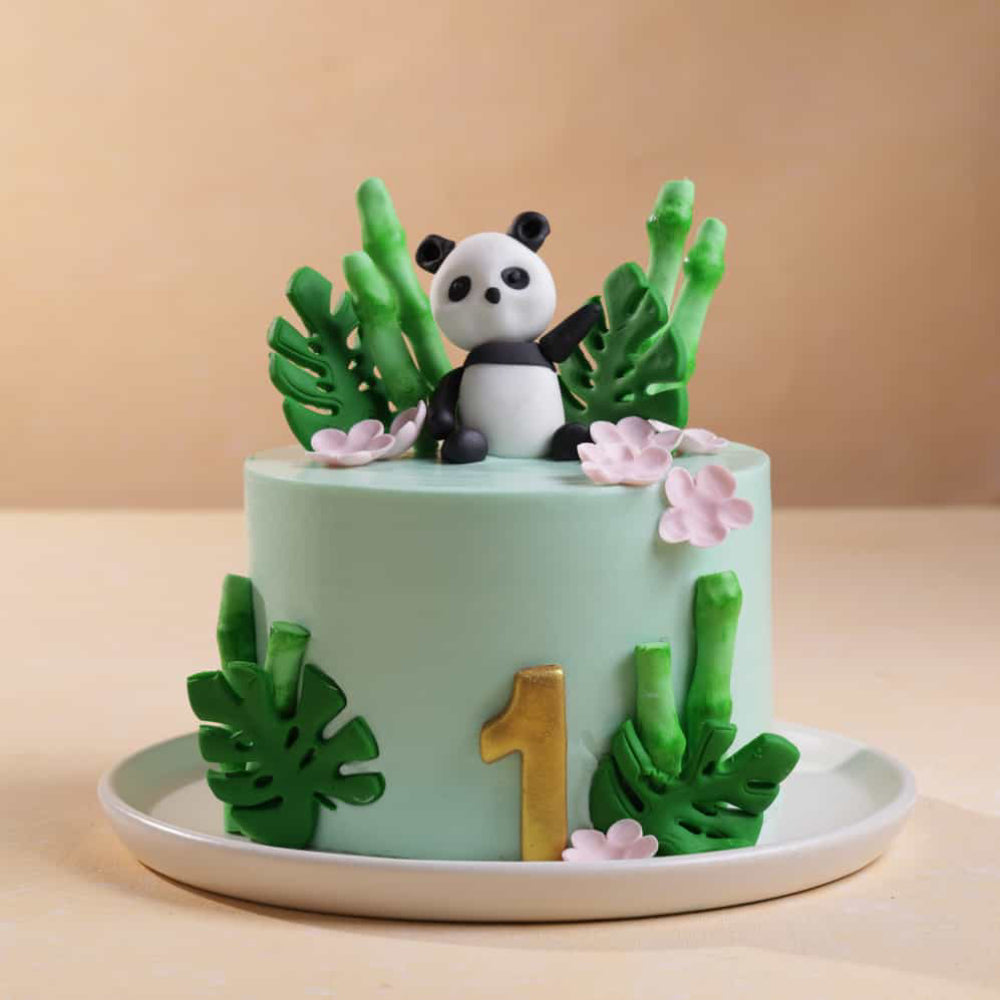 First birthday panda jungle theme cake with edible bamboo and tropical leaf decoration. Side view