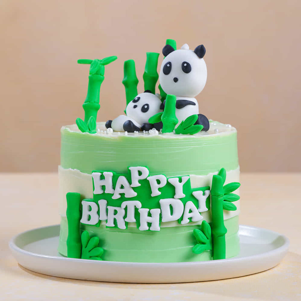 Panda themed birthday cake with green bamboo fondant decorations and edible pearl accents.