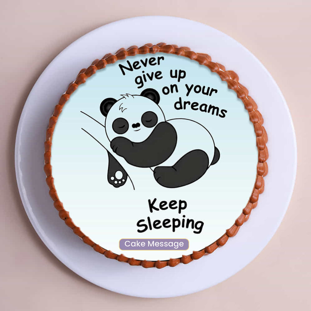 A round white frosted cake featuring a humorous edible image of a sleeping panda and motivational text. Top view