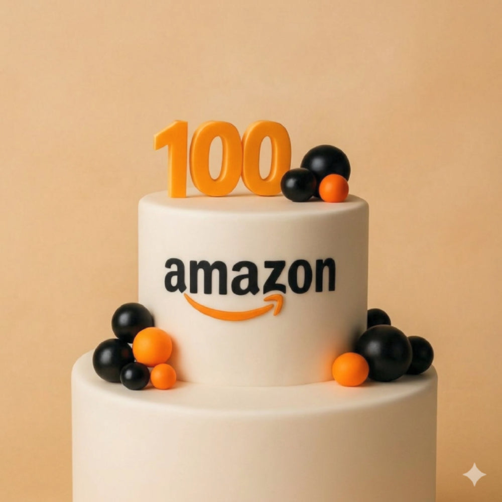 Two-tier Amazon milestone cake with "100" topper and orange and black sphere decorations.