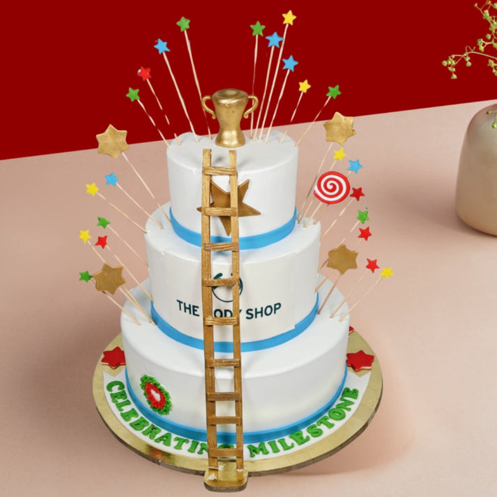 Three-tier cake with a golden ladder, trophy topper, and star decorations.