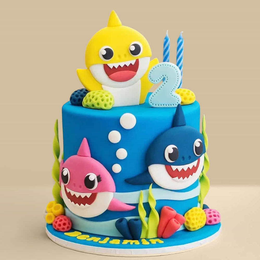 blue Baby Shark birthday cake with yellow, pink, and blue shark characters, coral decorations, and a number 2 topper. side view