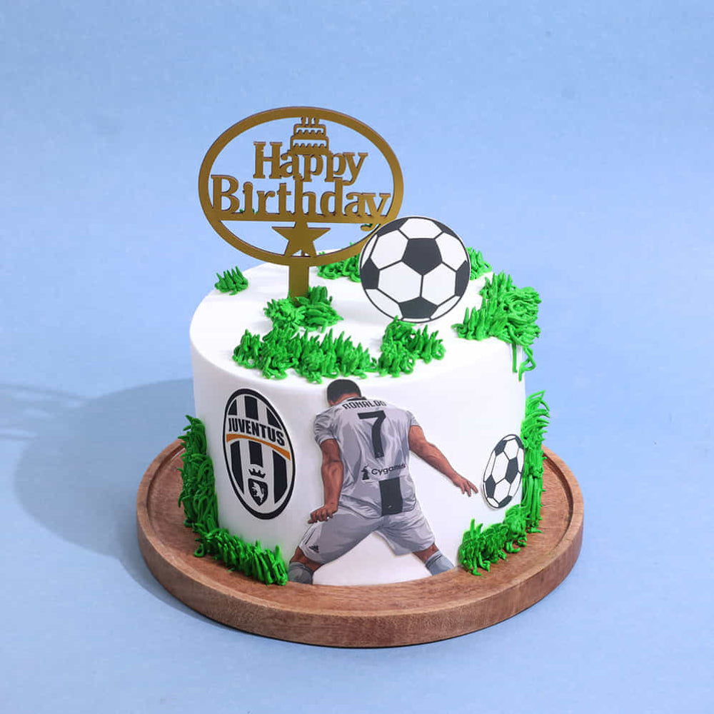 Birthday cake with soccer theme, including a player and ball, on a blue background