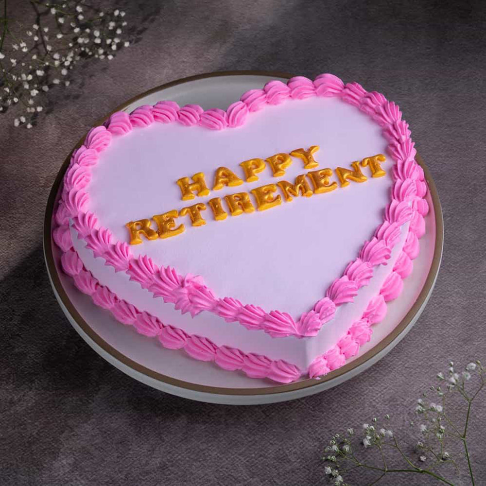 Pink heart-shaped cake with gold "Happy Retirement" written. top angle view 