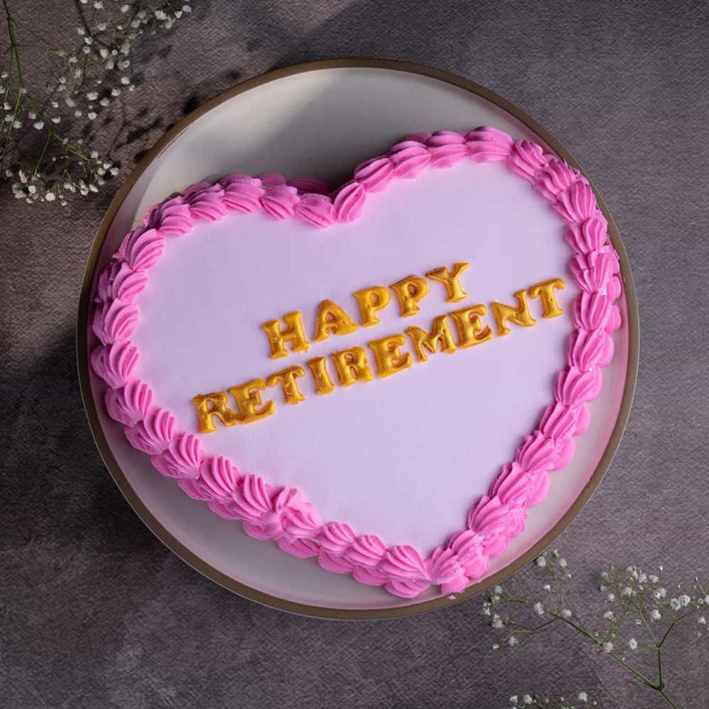 Pink heart-shaped cake with gold "Happy Retirement" written. top view 