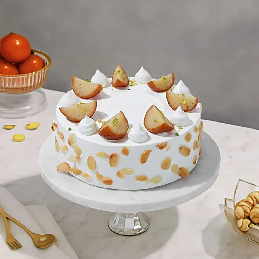 Gulab Jamun fusion cake with white frosting, almond flakes, and cream swirls. top angle view