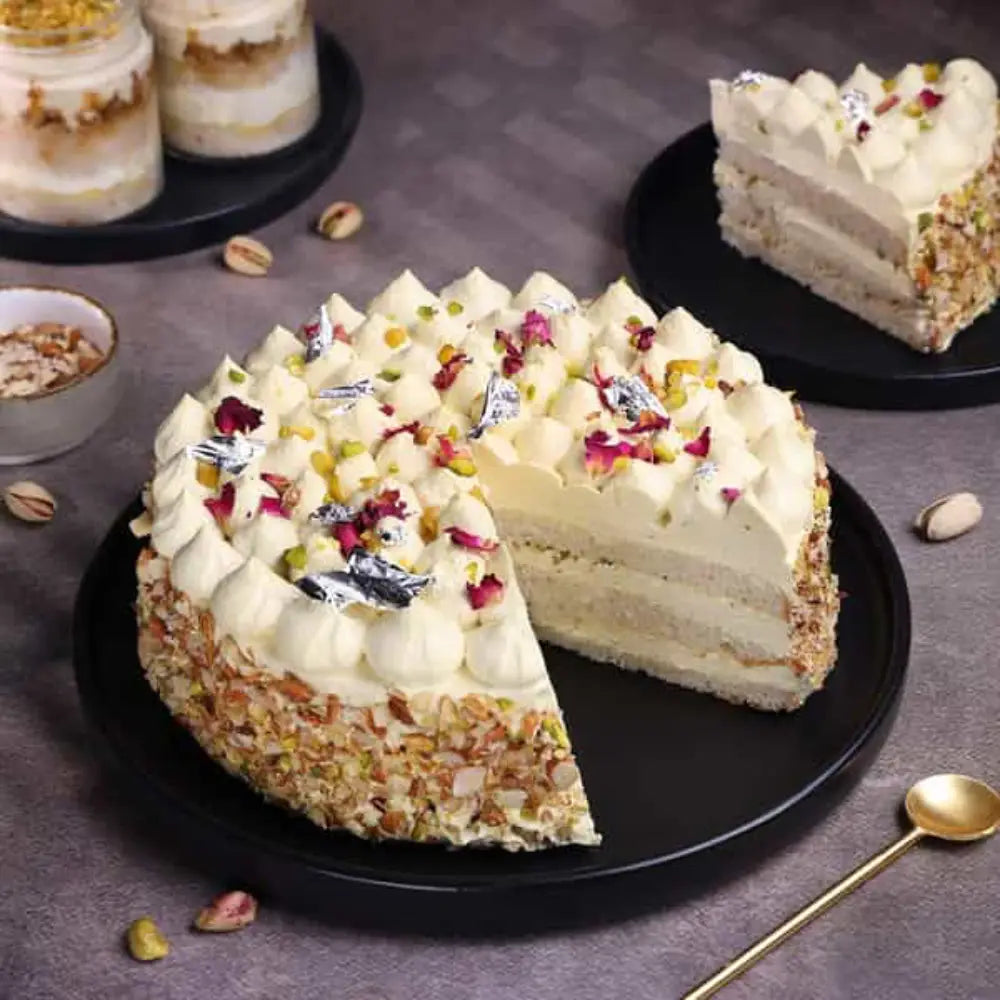 Elegant Thandai Gulkand Cake topped with rose petals, silver leaf, and crushed nuts.