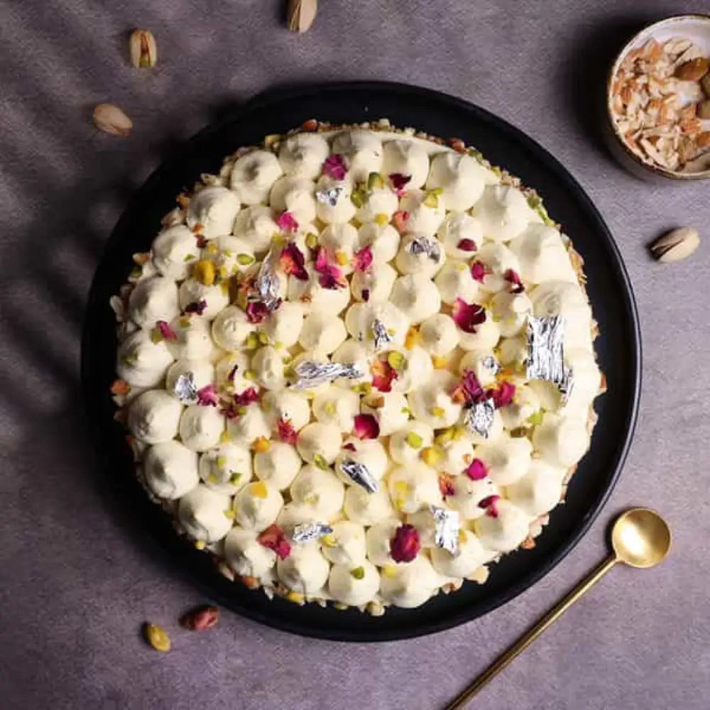 Elegant Thandai Gulkand Cake topped with rose petals, silver leaf, and crushed nuts. top view
