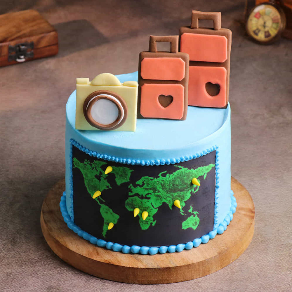 Blue travel cake with world map, camera, and suitcase toppers.