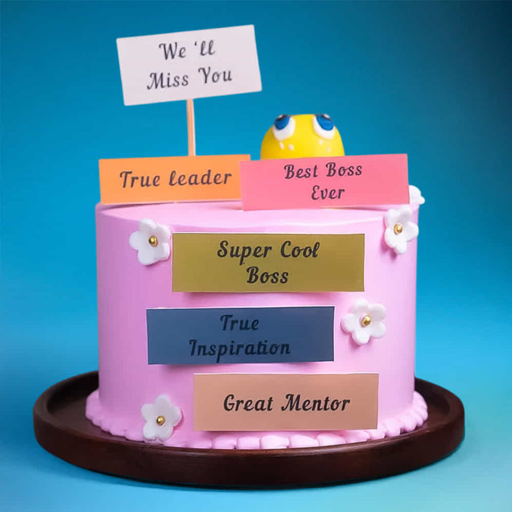 Pink farewell cake for a boss with a sad emoji and "We'll Miss You" messages. side view